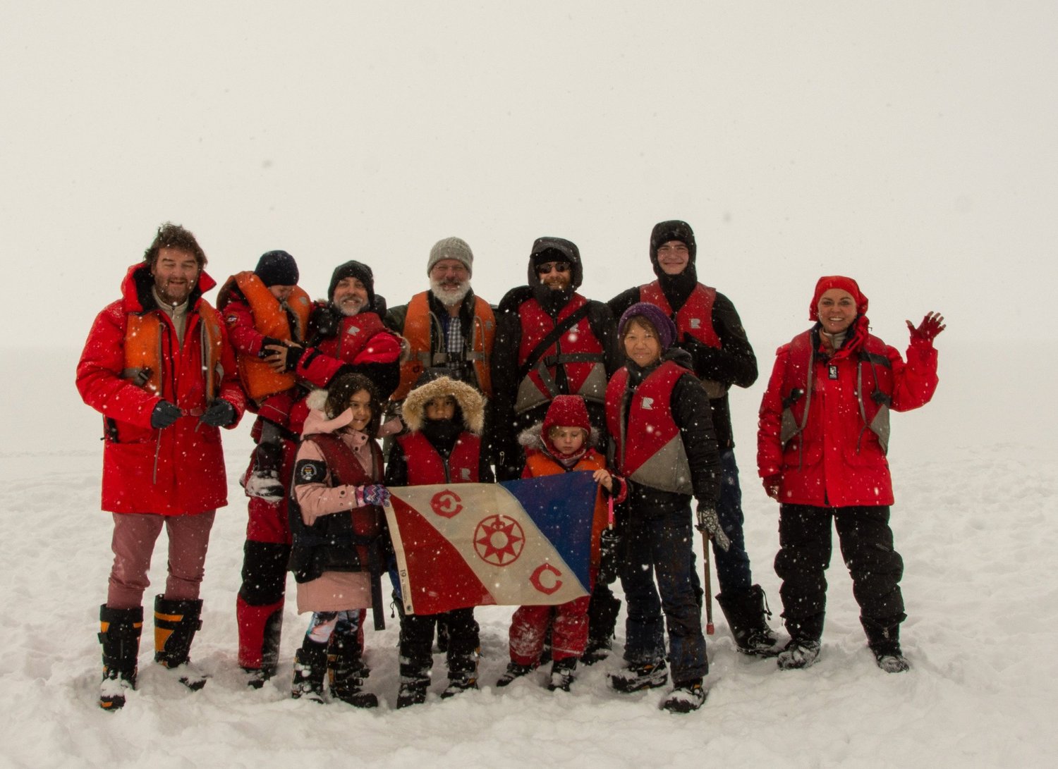 Families gathered on the Arctic ice with the Explorers Club flag